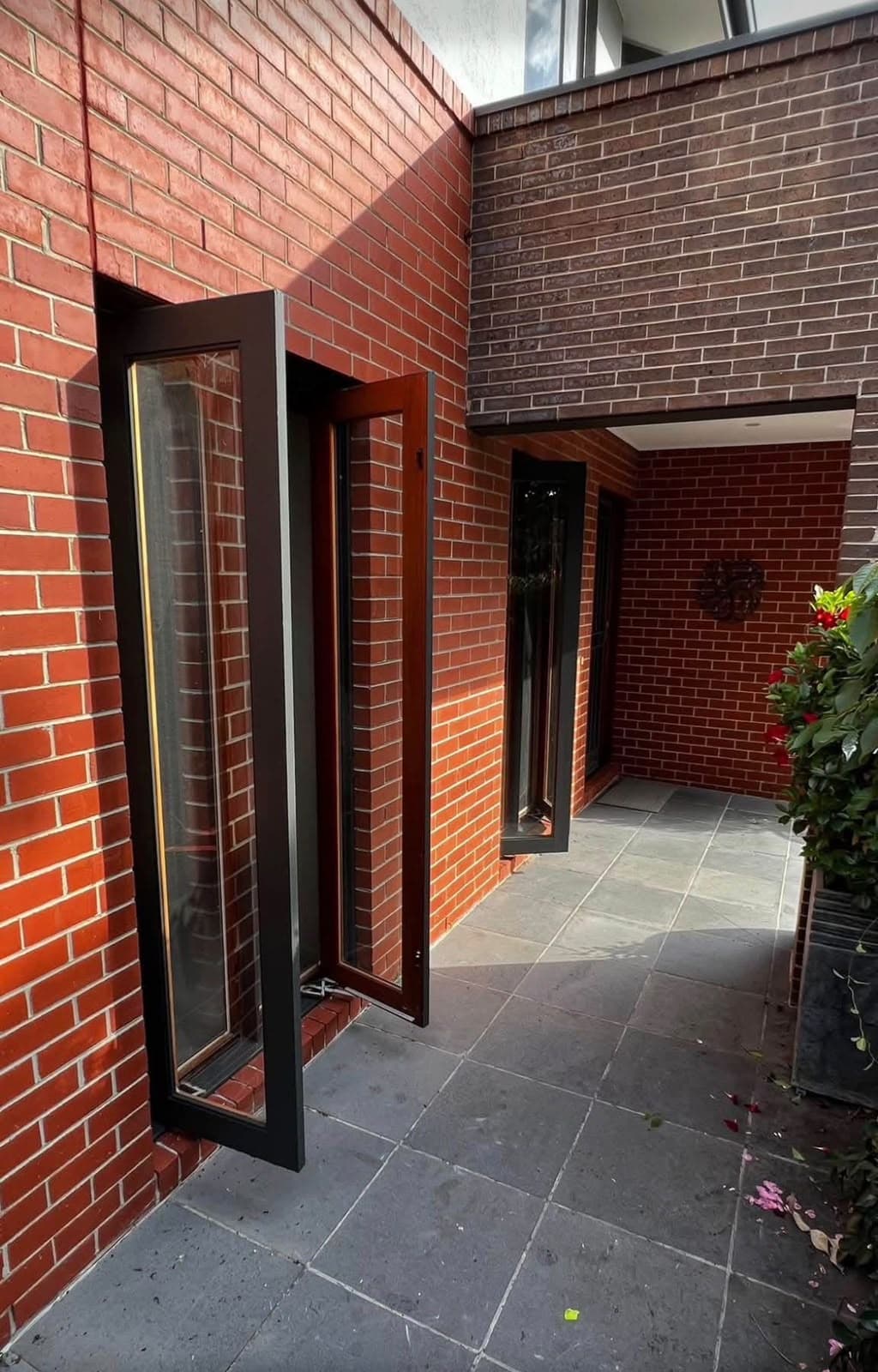Dark timber and glazed joinery opening onto a brick courtyard