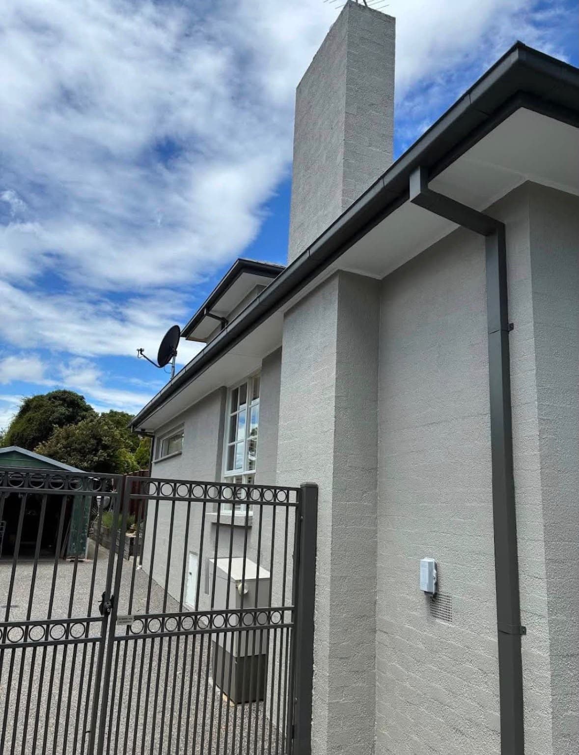 Grey rendered cottage exterior with charcoal guttering and gate