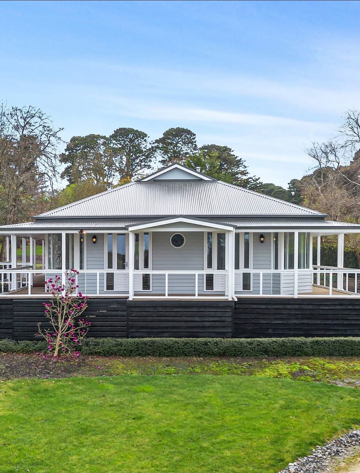 Grey weatherboard house with a crisp white wraparound veranda