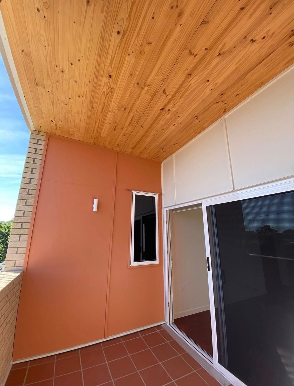 Covered balcony with warm orange walls and timber ceiling