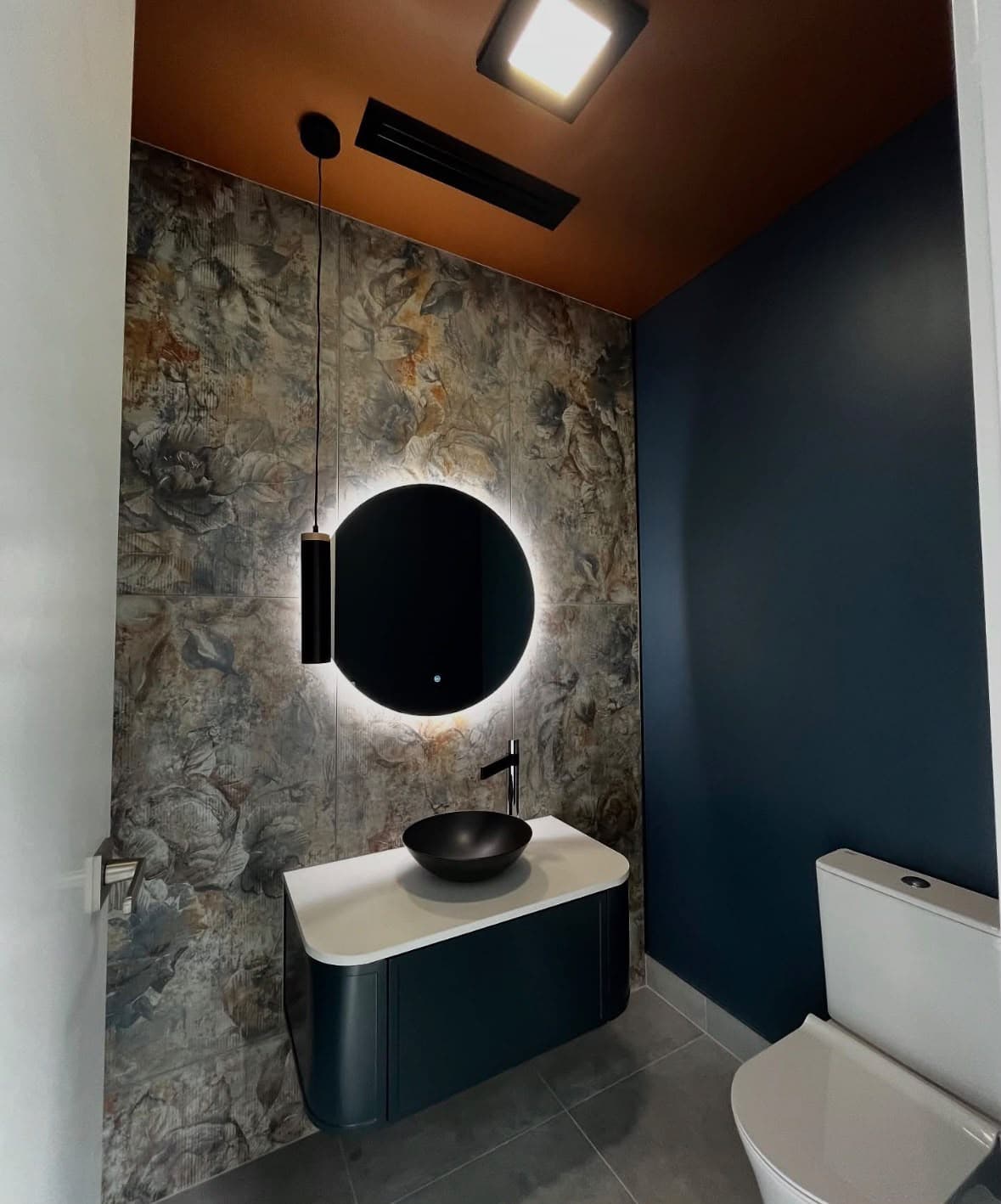 Powder room featuring deep blue walls and a warm orange ceiling