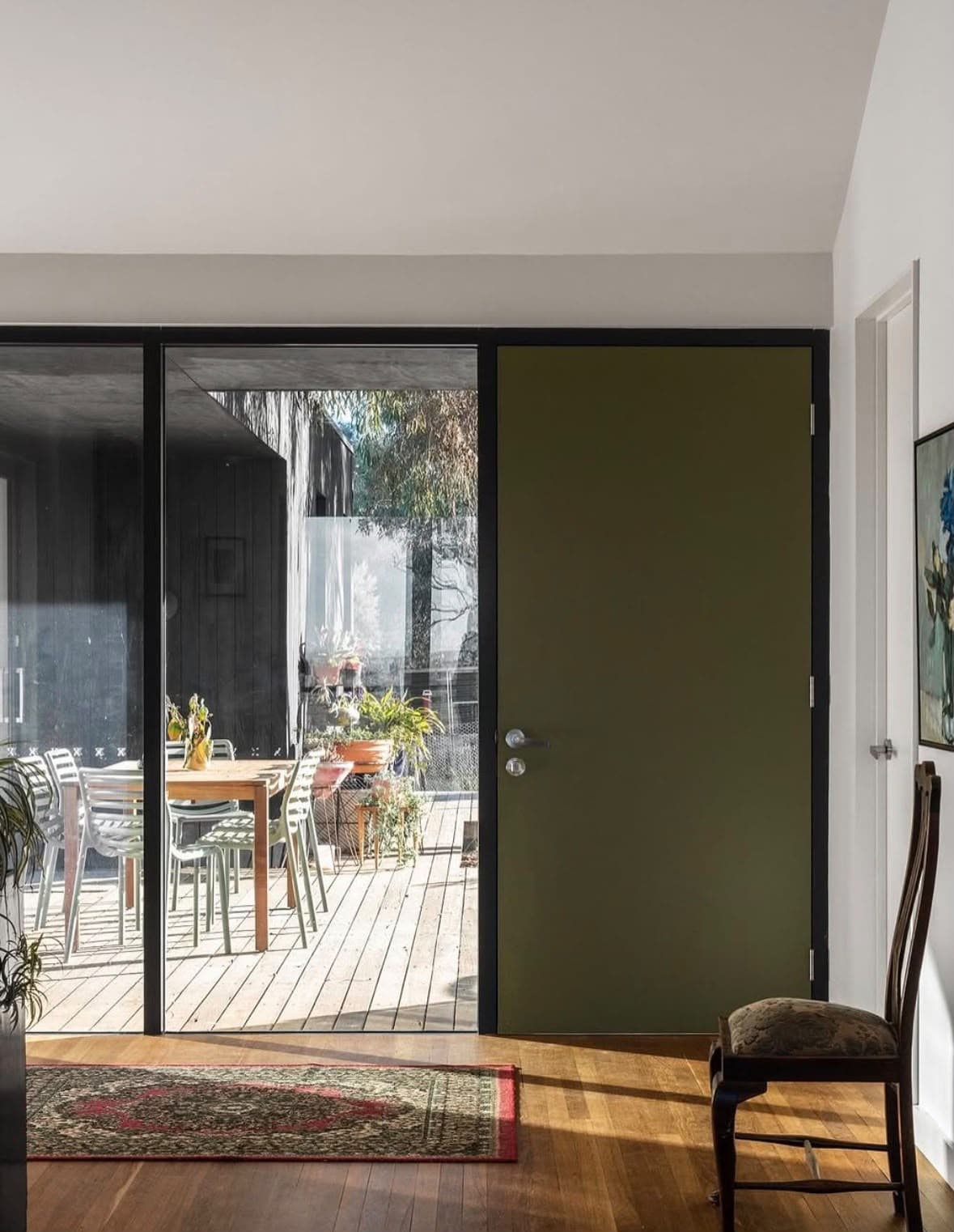 Deep green entry door adding colour to a bright interior
