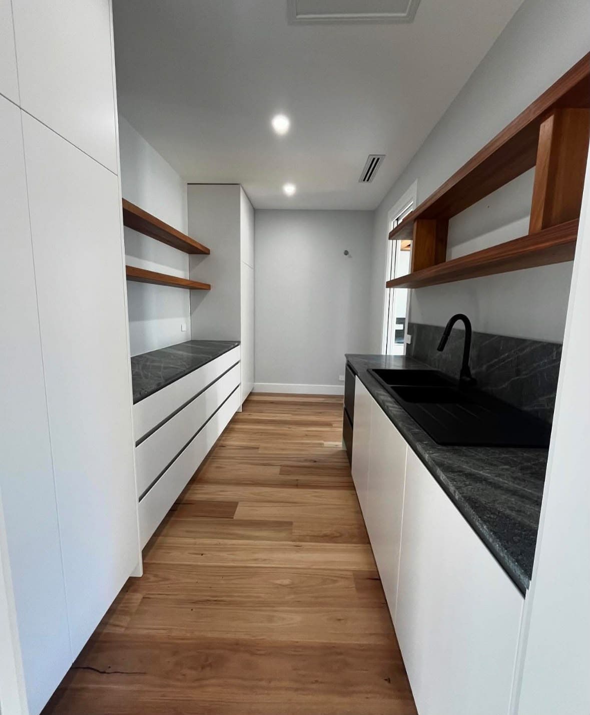 White butler's pantry with clean walls and timber shelving