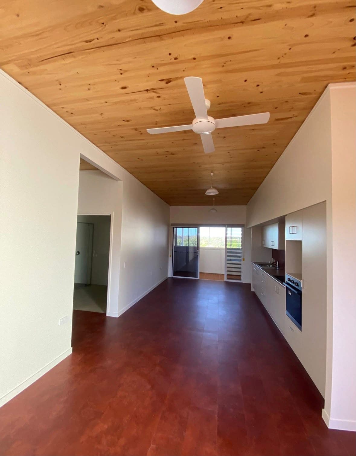 Open interior with white walls beneath a natural timber ceiling