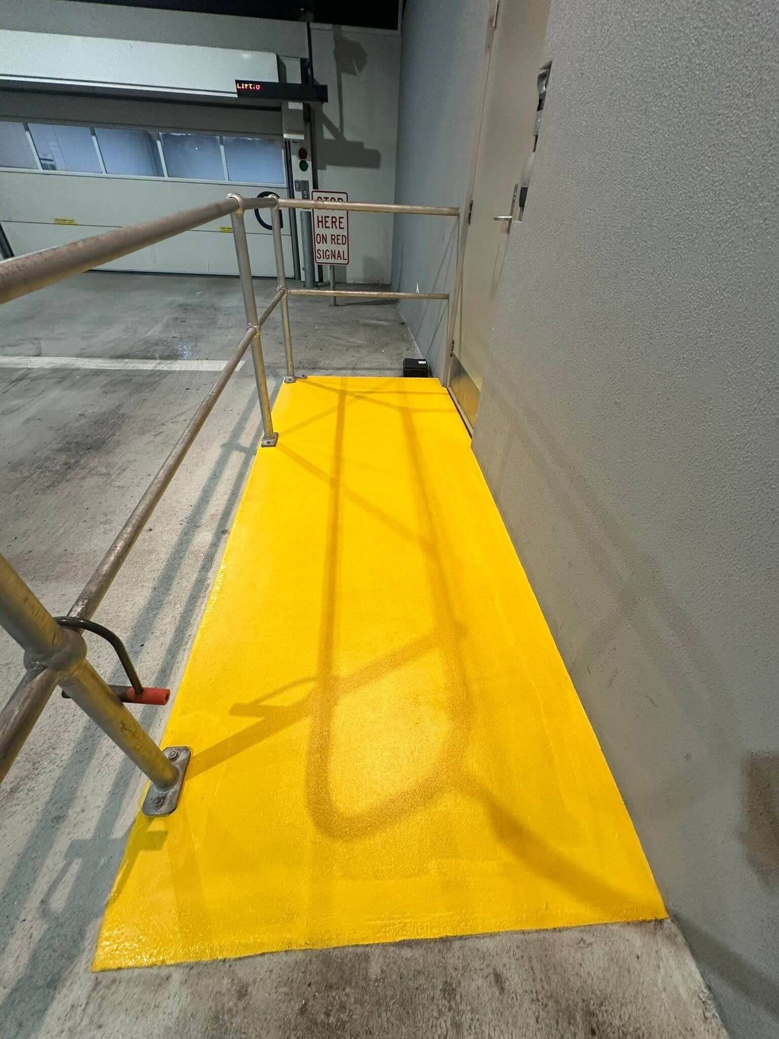 Finished yellow safety walkway coating beside a loading bay