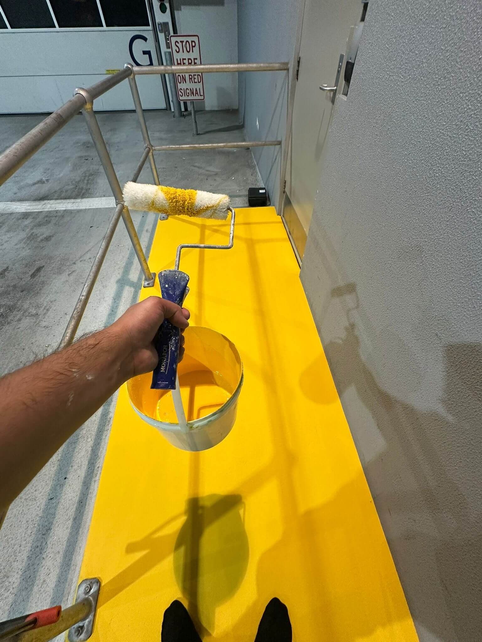 Painter applying a yellow safety walkway coating