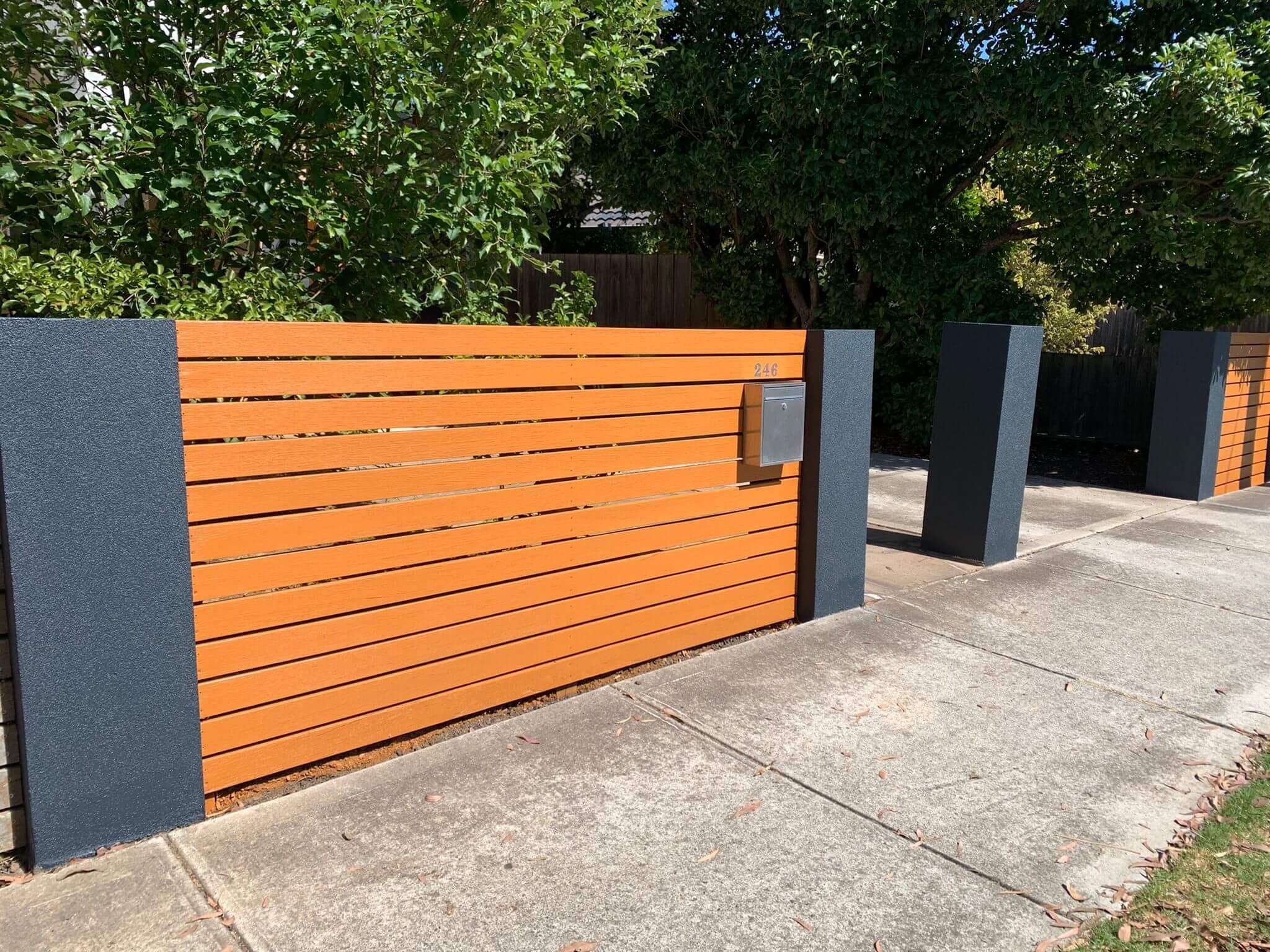 Restored timber slat fence with freshly coated charcoal pillars