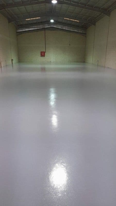 Glossy protective floor coating across a large warehouse