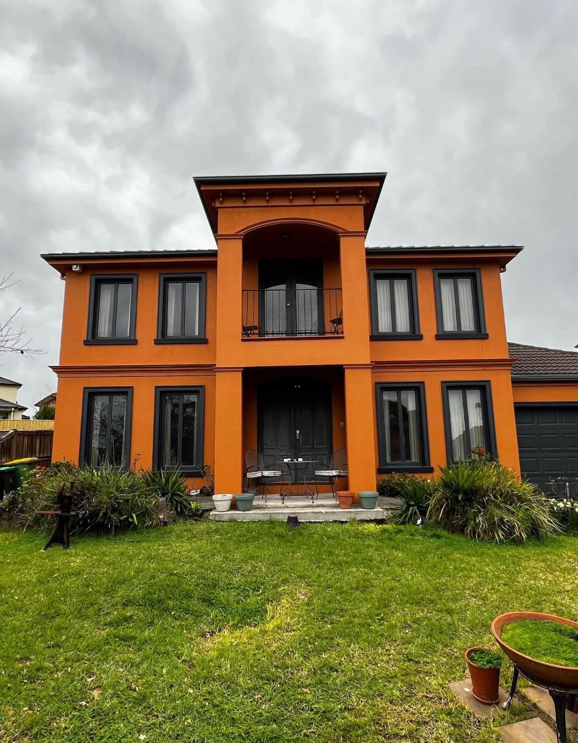 Two-storey rendered home finished in warm orange with dark trim