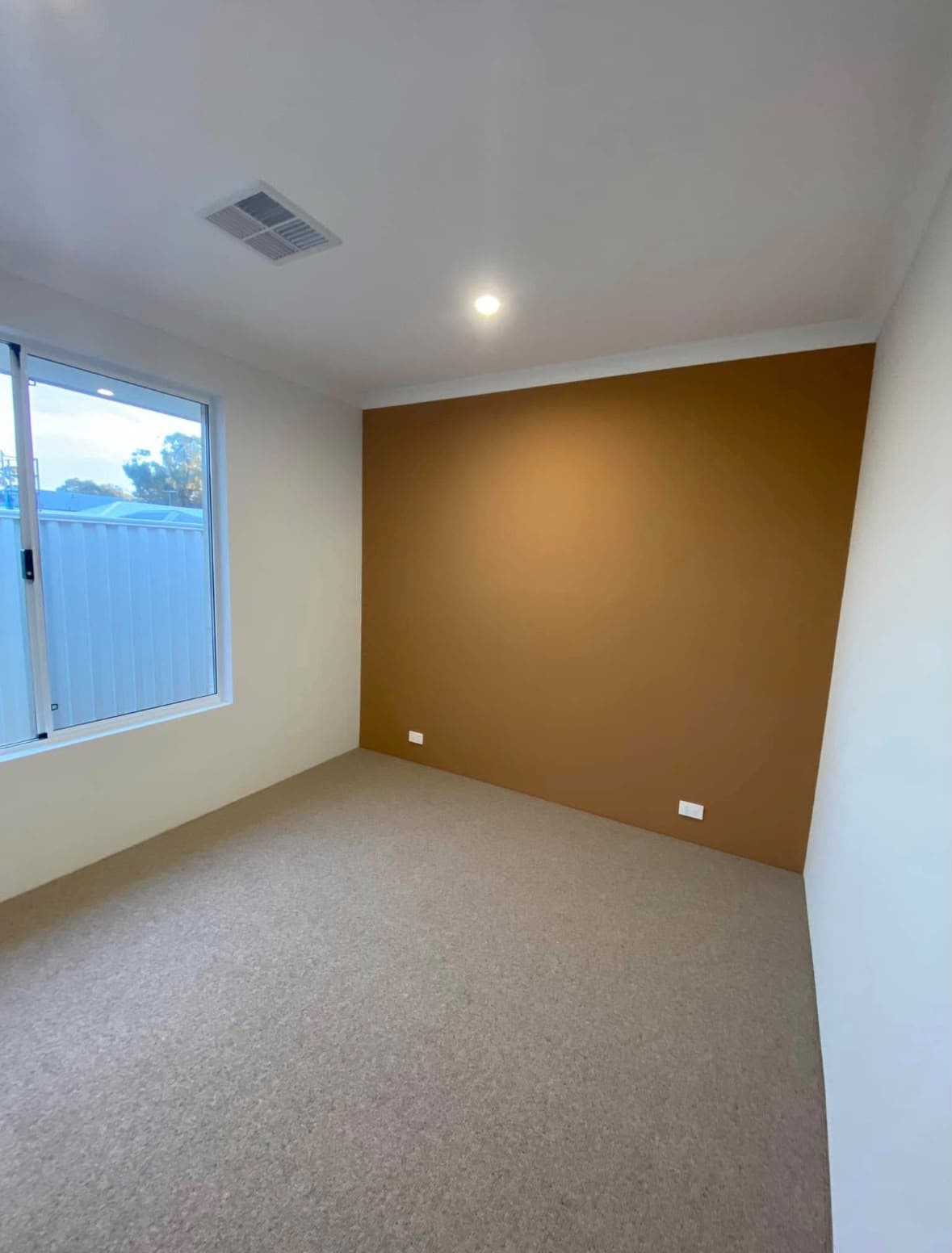 Bedroom finished with a warm ochre feature wall
